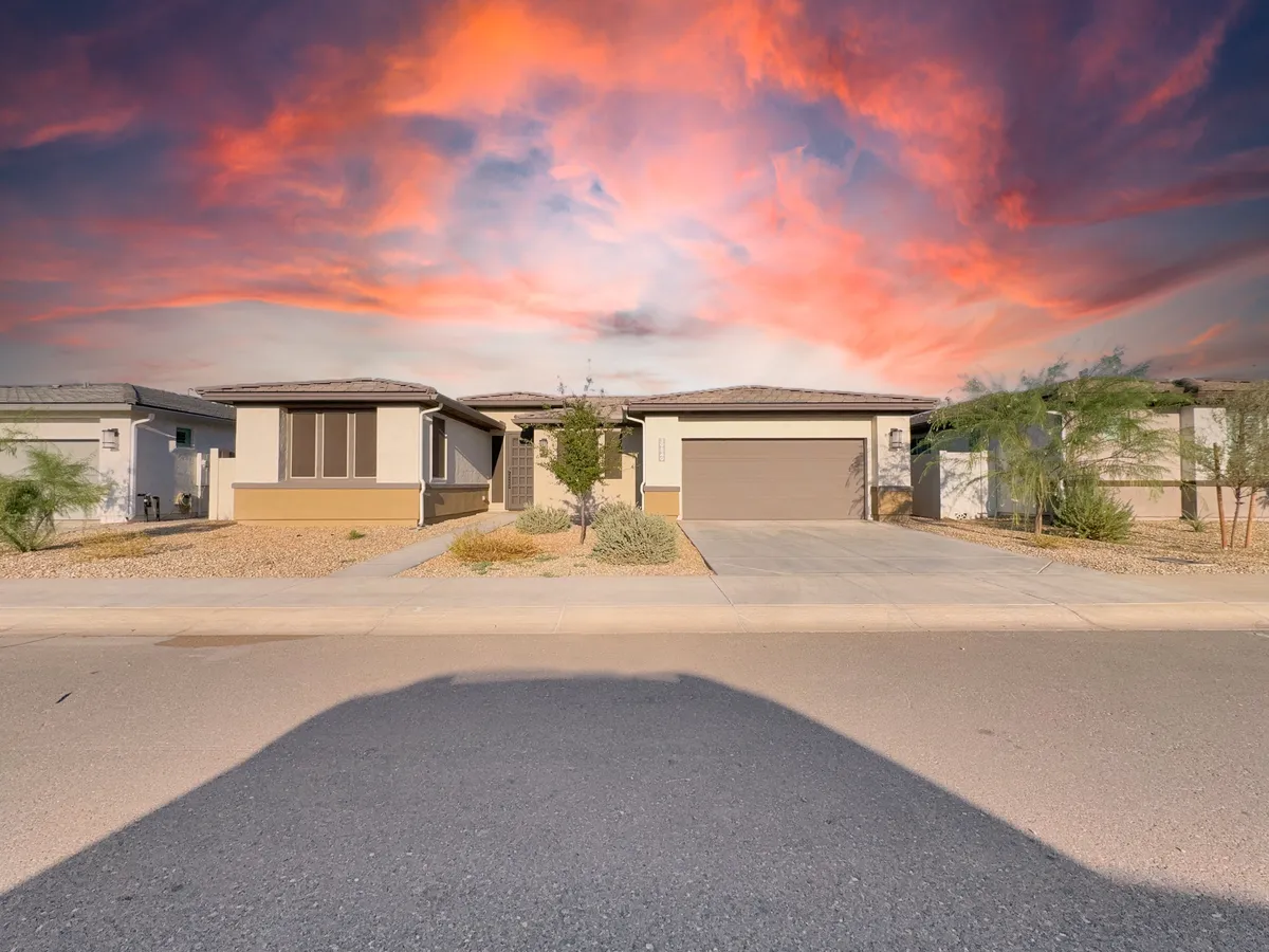 This exterior shot captures the modern architecture of the home, a beautifully landscaped front yard, and a breathtaking sunset sky. The curb appeal and inviting ambiance set the tone for welcoming guests and enjoying evening relaxation outdoors.
