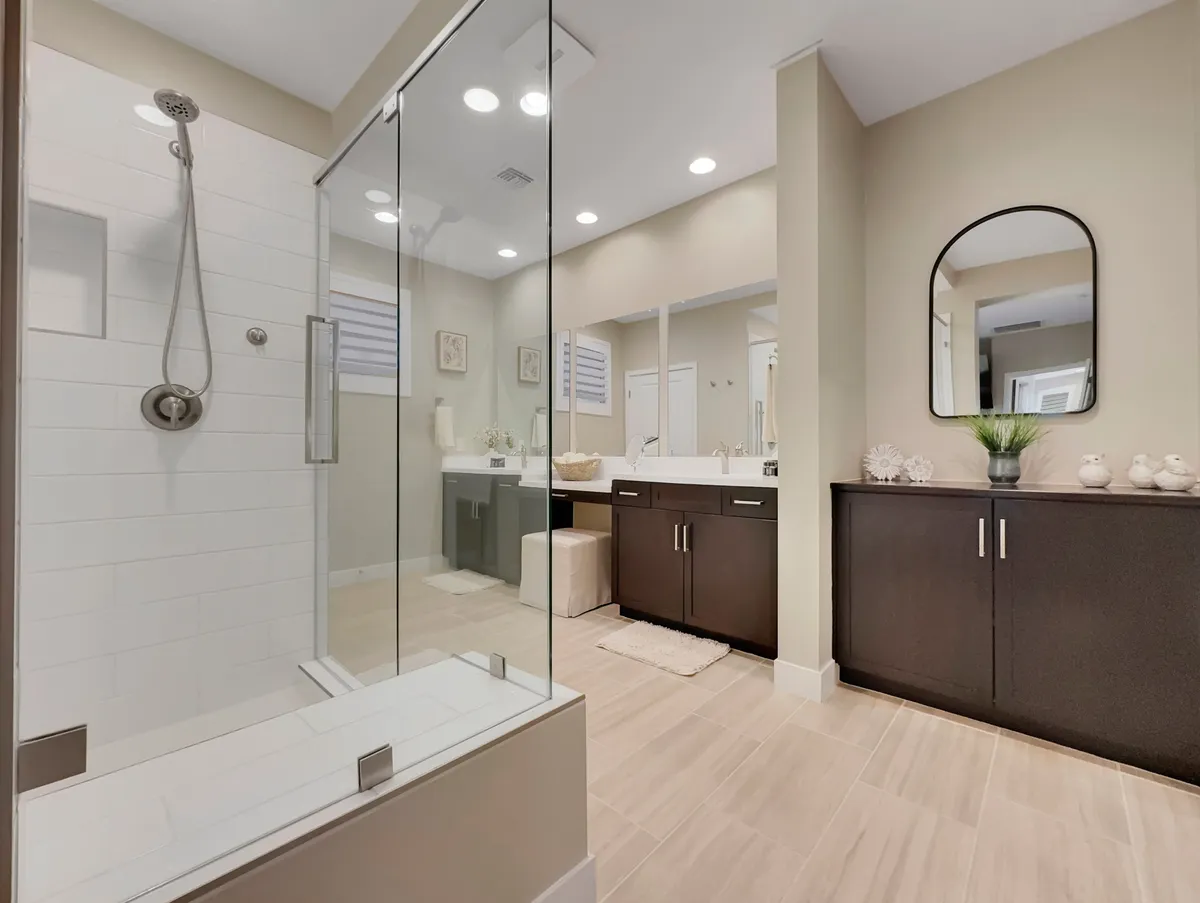 A modern en-suite bathroom with a sleek glass shower enclosure, double vanity, and dark cabinetry, all highlighted by a serene, spa-like ambiance.