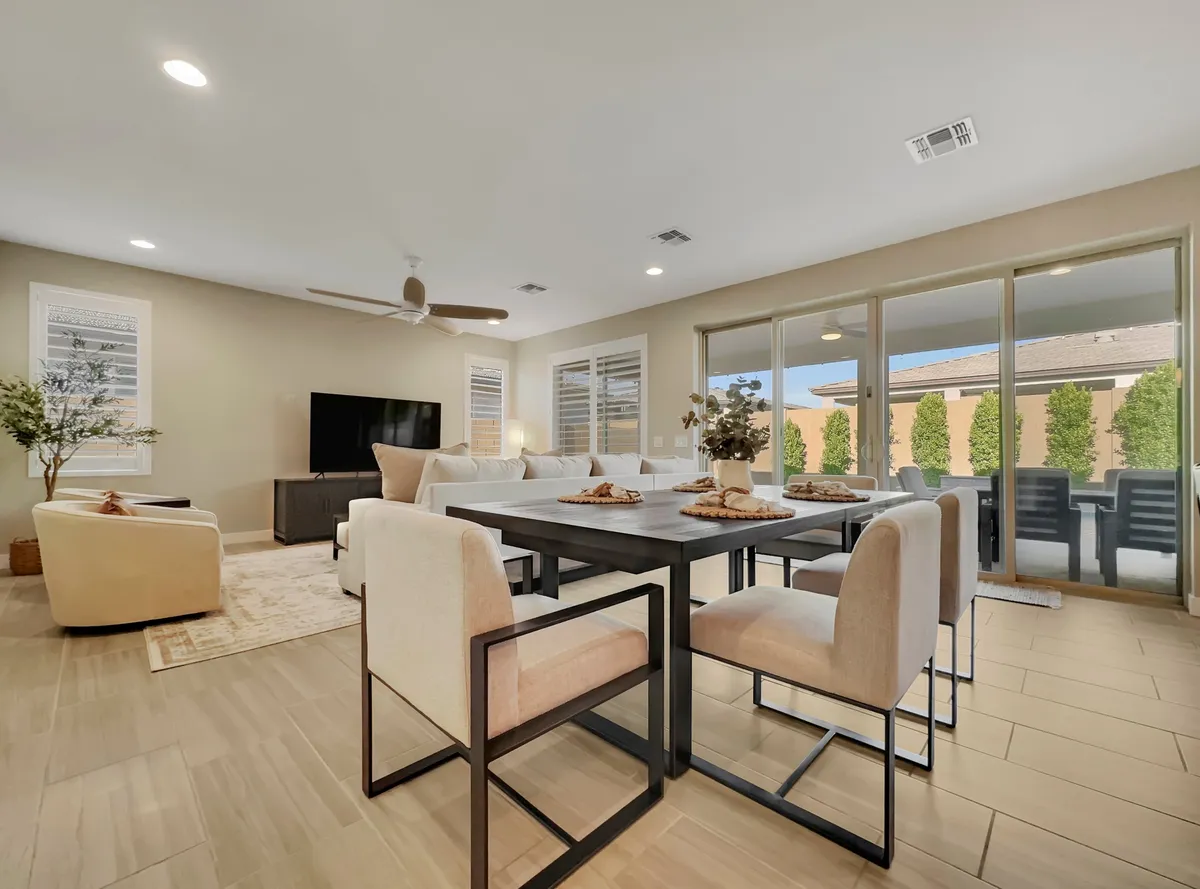 A bright, open-plan space featuring a dining table elegantly set with decorative items, a comfortable seating area adjoining the dining space, and large windows that flood the area with natural light. The harmonious layout seamlessly blends dining and living, while the upscale accents and furnishings underscore a sense of everyday luxury.